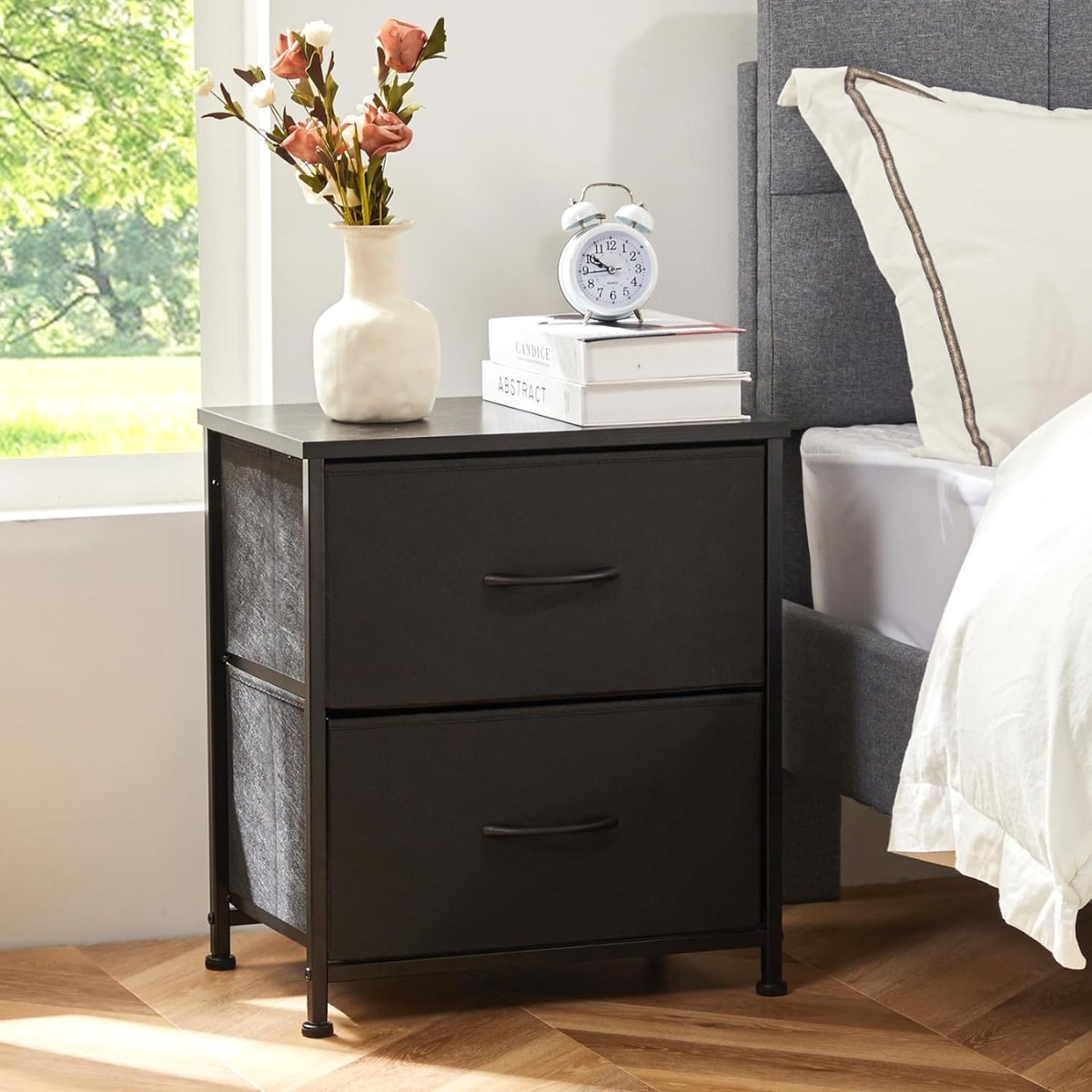 2-drawer nightstand on left side of bed with vase, books, and clock on top.